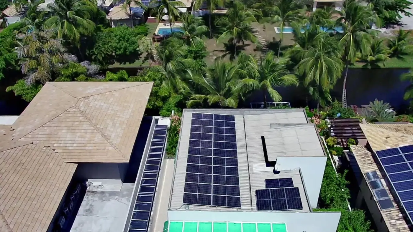 Sistema fotovoltaico no telhado de uma casa com piscina, visto de drone