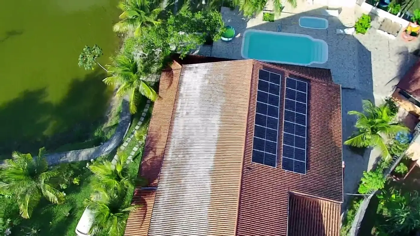 Residência com piscina e módulos fotovoltaicos na cobertura, vista aérea