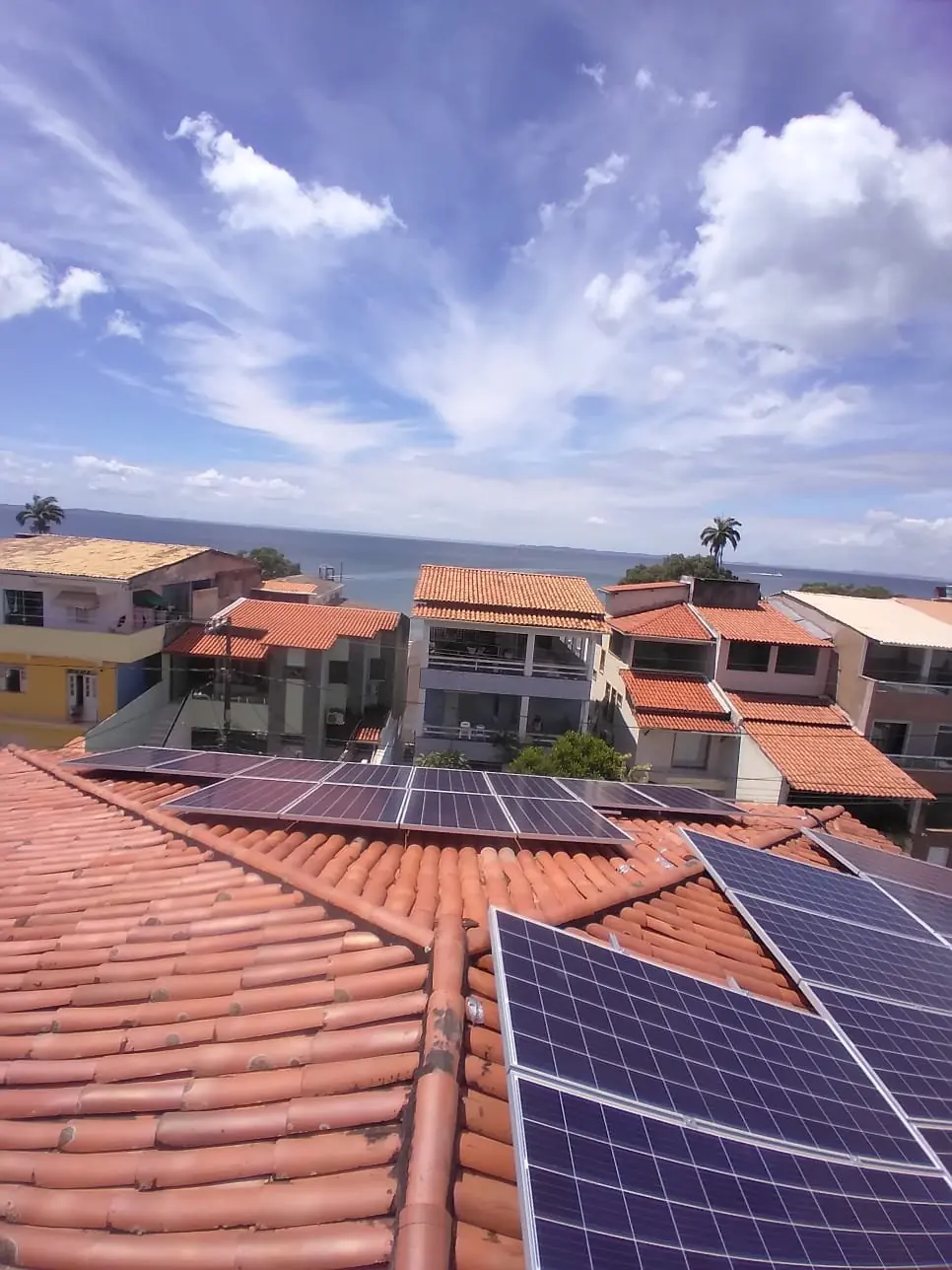 Módulos fotovoltaicos em telhado cerâmico com vista para o mar