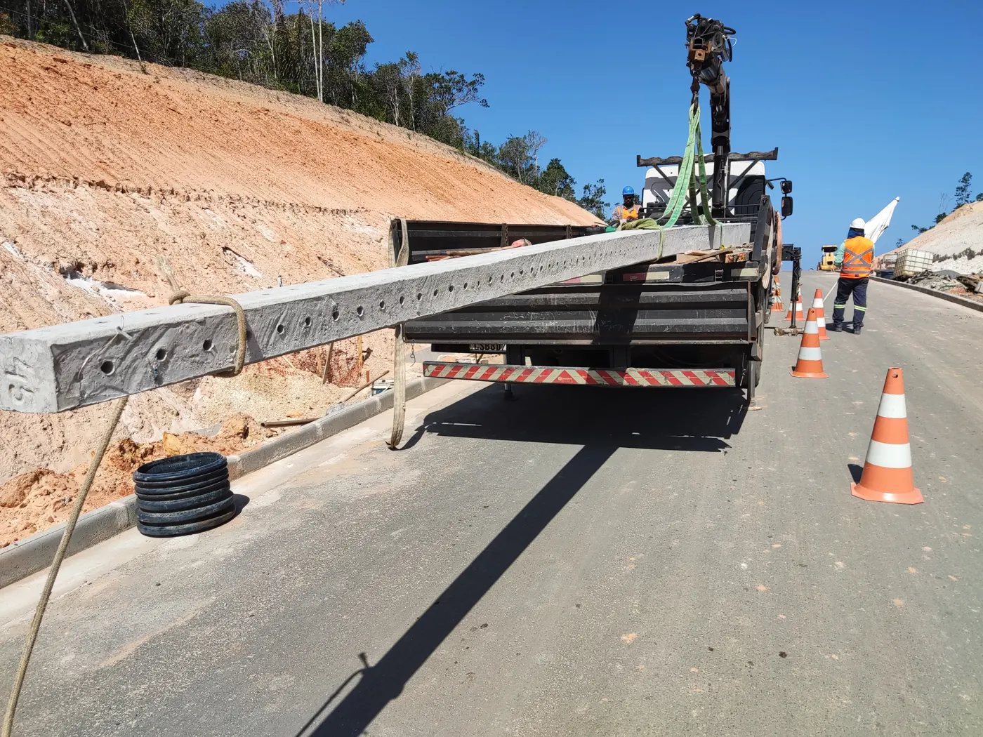 Postes descarregados com caminhão guindauto para expansão de rede de média tensão